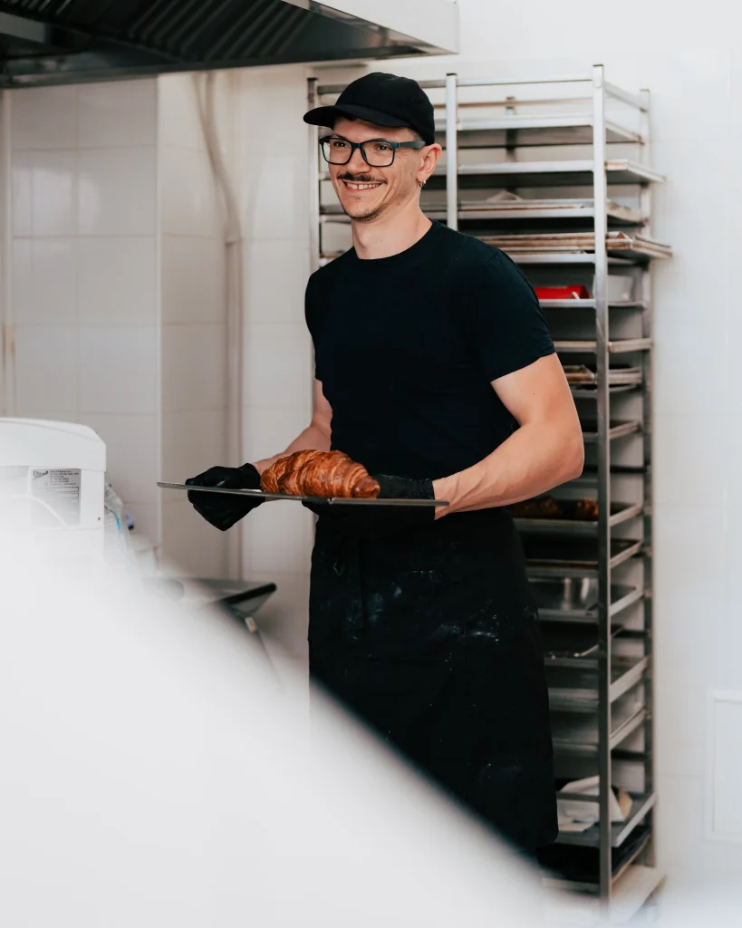 Pasticcere con una teglia di croissant
